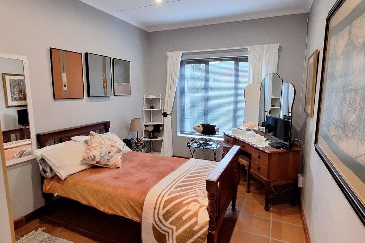 A cozy bedroom featuring tiled flooring, neutral wall finishes, and a window with fitted blinds, providing a functional and comfortable living space.