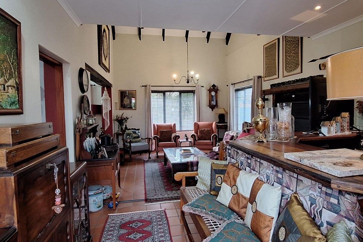 Spacious living area featuring high vaulted ceilings with exposed beams, tiled flooring, and a built-in bar counter, creating a warm and inviting atmosphere.
