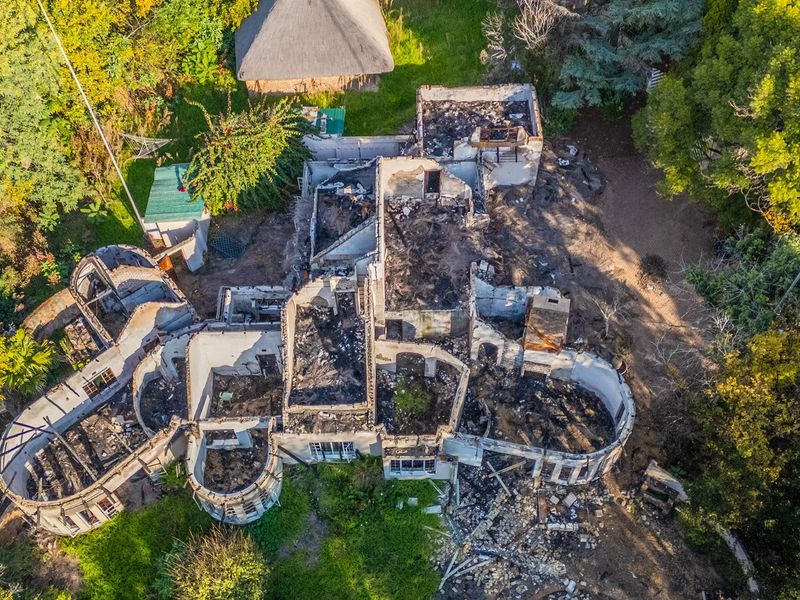 Aerial view of a residential property showing extensive fire damage and structural destruction of the main dwelling.