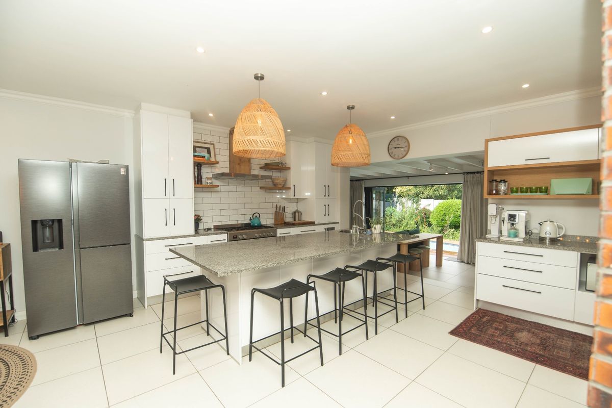 Modern kitchen featuring a large granite island, white cabinetry, subway tile backsplash, and seamless flow to the outdoor patio area.