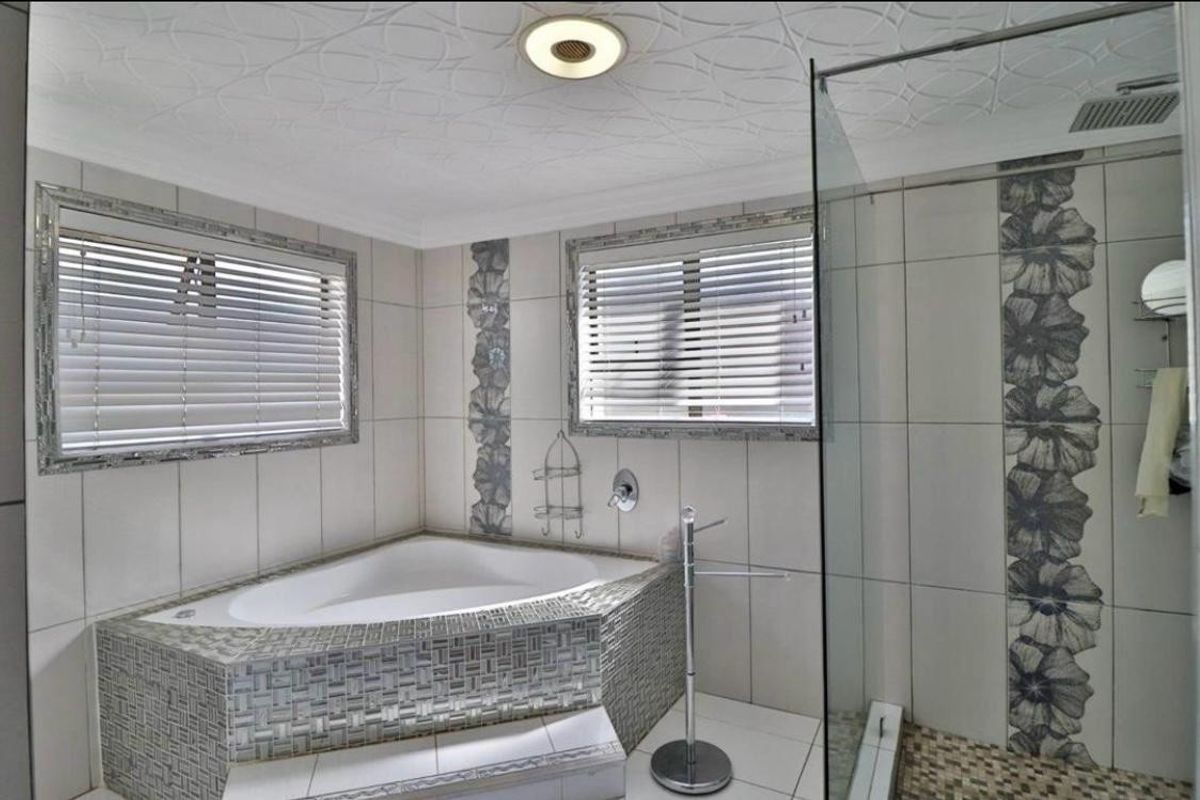 A bathroom featuring a corner soaking tub, a glass-enclosed shower, and decorative tiled accents throughout the space.