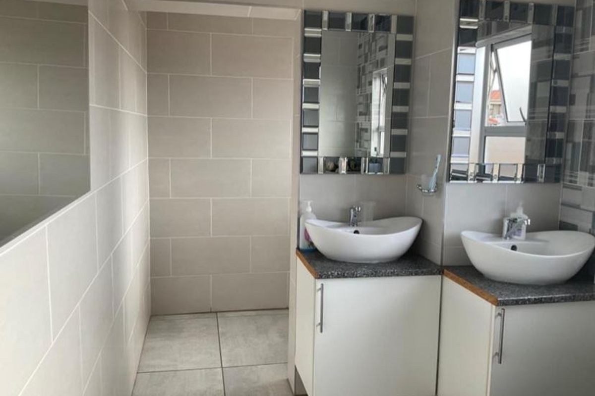 Modern bathroom featuring a double vanity with vessel sinks, tiled walls, and large mirrors.