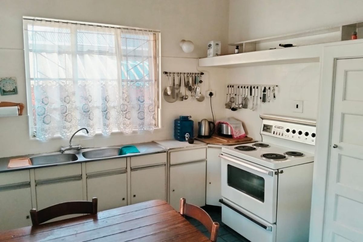 A functional kitchen featuring a double-basin sink, built-in cabinetry, and a freestanding electric stove with an oven.