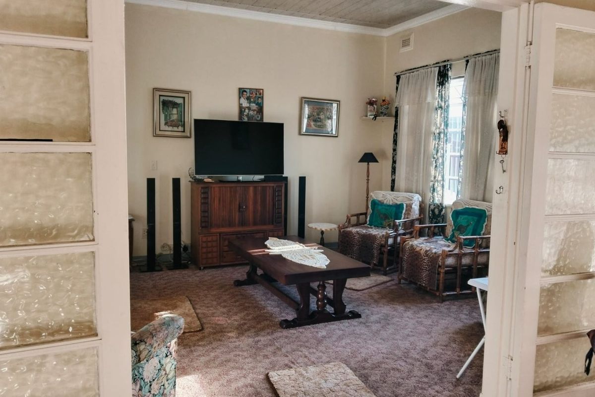 A living room featuring traditional architectural details, including textured ceiling panels and classic glass-paneled double doors.