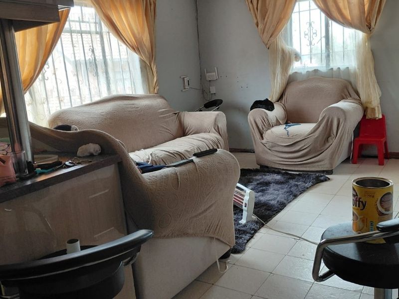 Open plan living area featuring tiled flooring and security bars on windows, requiring cosmetic updates to improve the overall aesthetic and condition.
