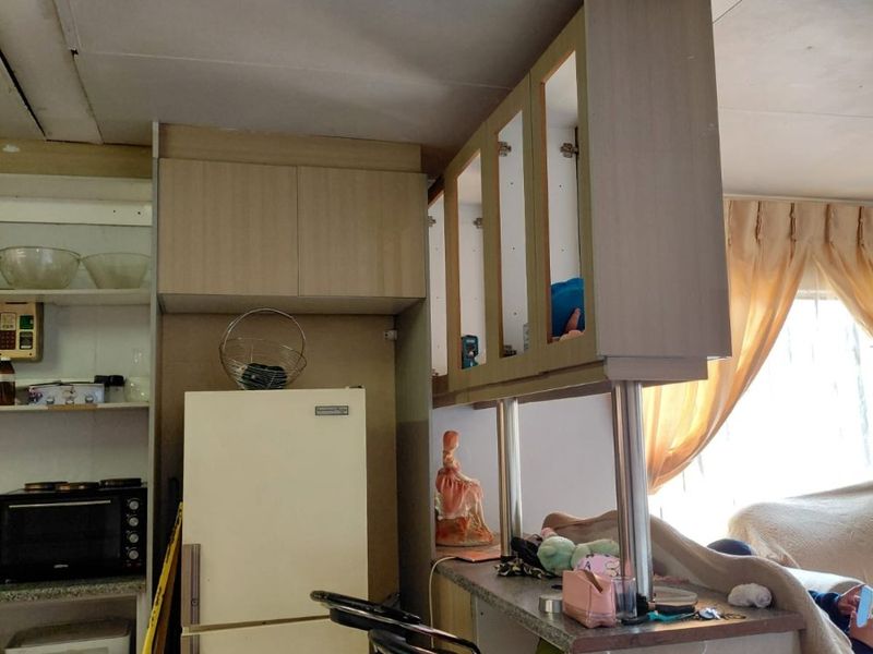 A dated kitchen area featuring built-in cabinetry and a breakfast bar, showing signs of wear and requiring cosmetic updates.