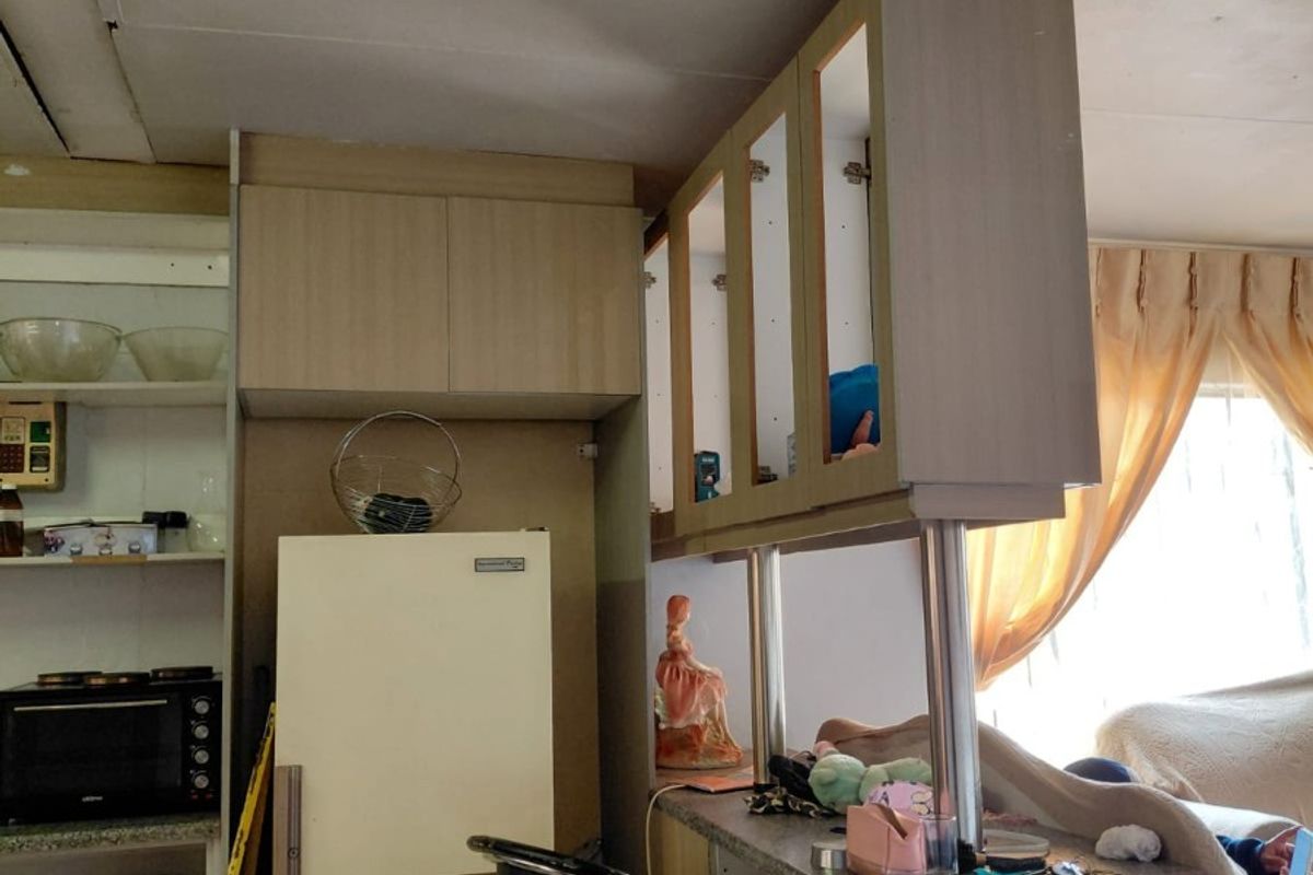 A dated kitchen area featuring built-in cabinetry and a breakfast bar, showing signs of wear and requiring cosmetic updates.
