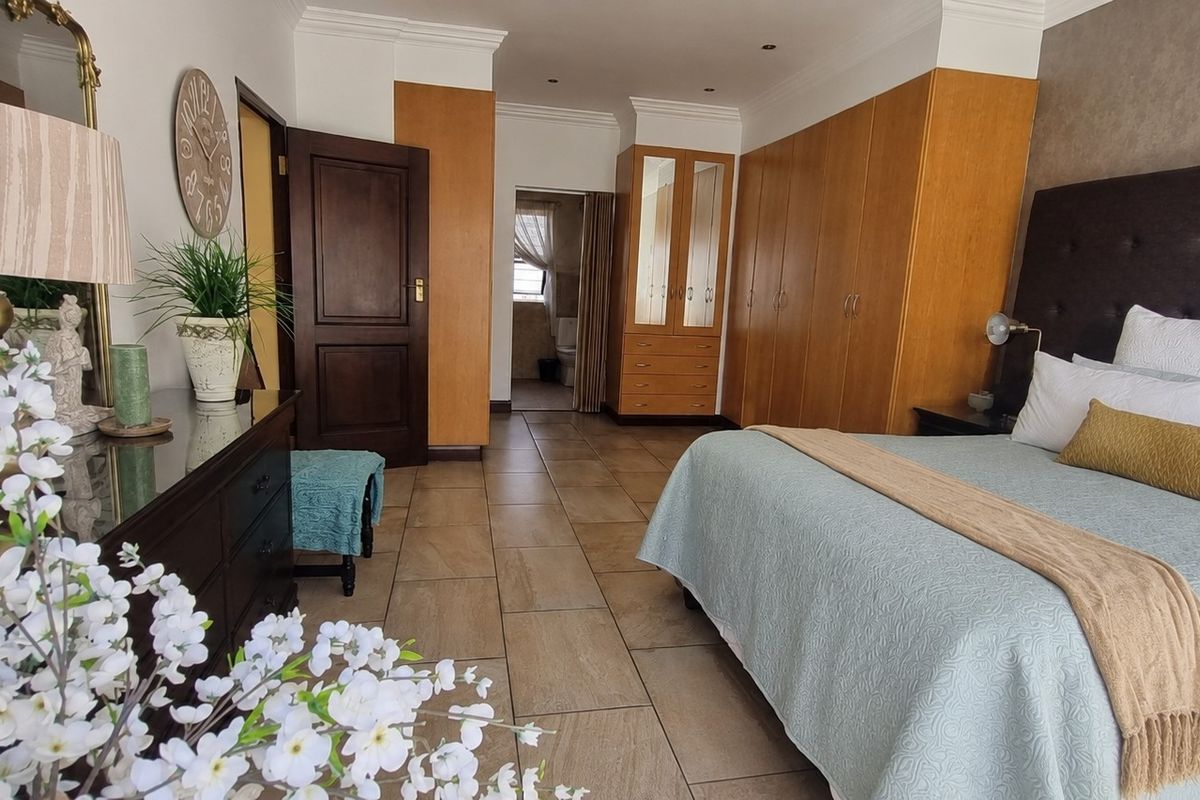 Spacious bedroom featuring built-in wooden cabinetry, tiled flooring, and an en-suite bathroom access.