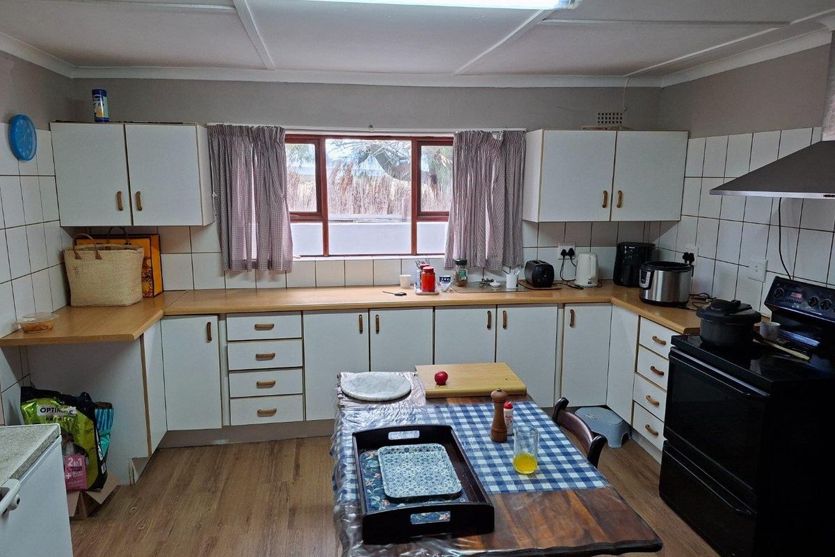 A functional kitchen featuring white cabinetry, wood-look laminate countertops, a tiled splashback, and a built-in extractor fan.