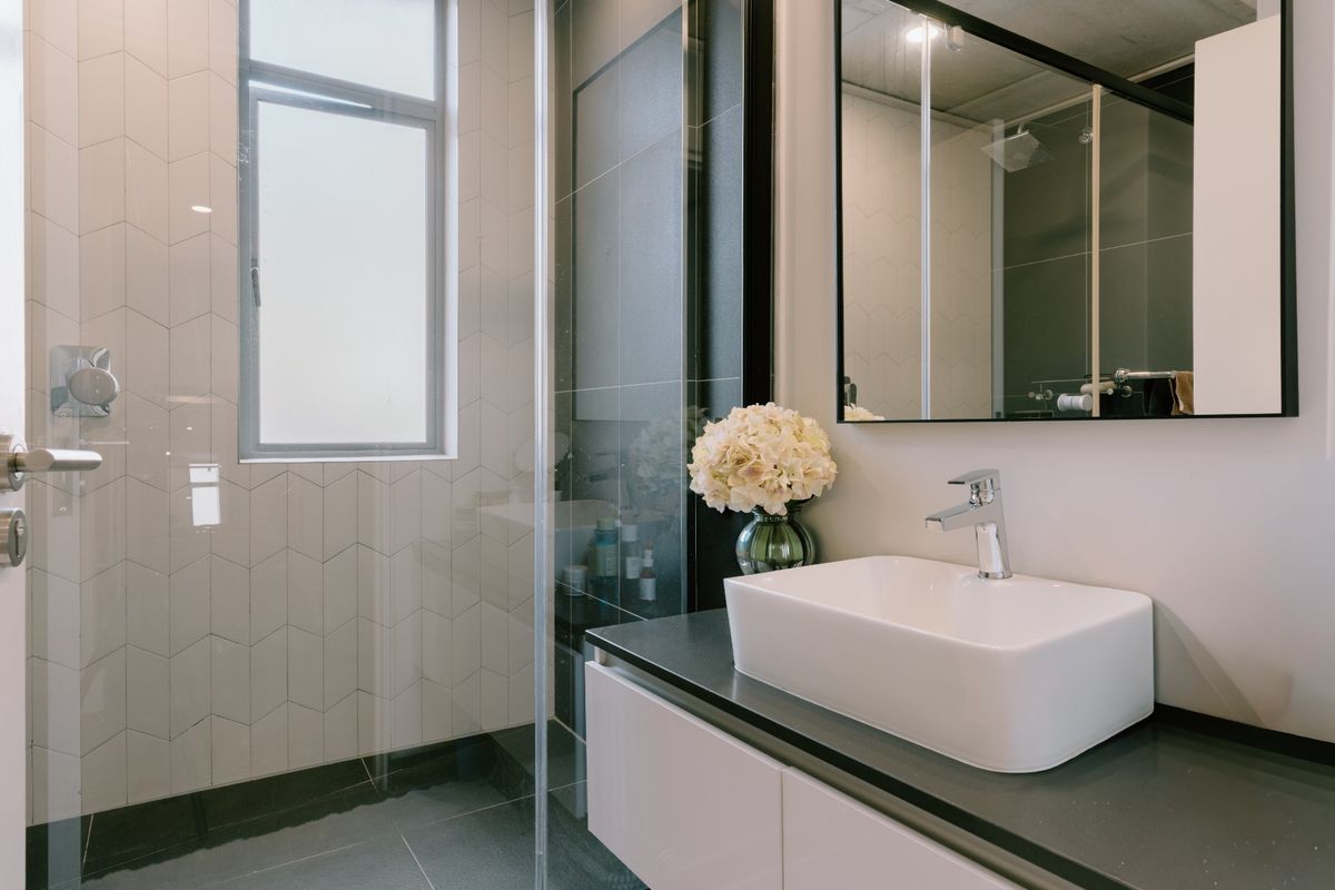 Modern bathroom featuring a sleek vessel sink, floating vanity, glass-enclosed shower, and contemporary geometric wall tiling.
