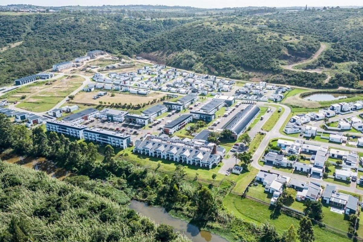 Aerial view of a modern residential apartment complex and surrounding estate, featuring landscaped grounds and proximity to natural green belts.