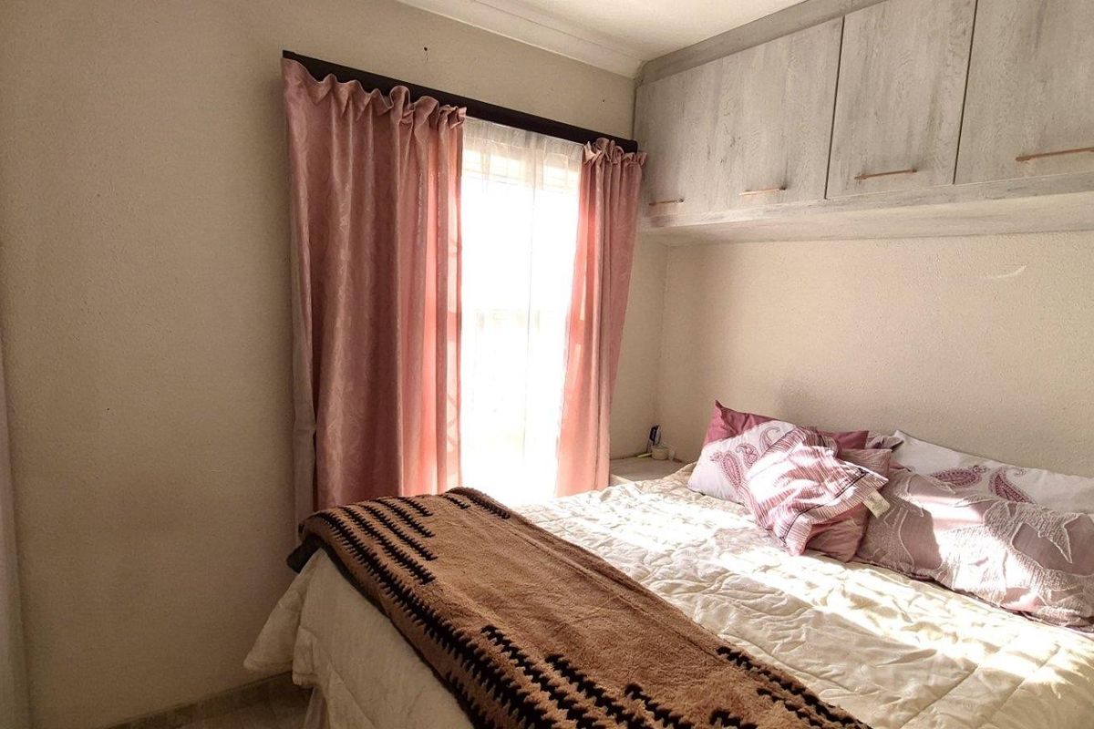 A bedroom featuring built-in cupboards and overhead storage units, providing practical storage solutions within the room.