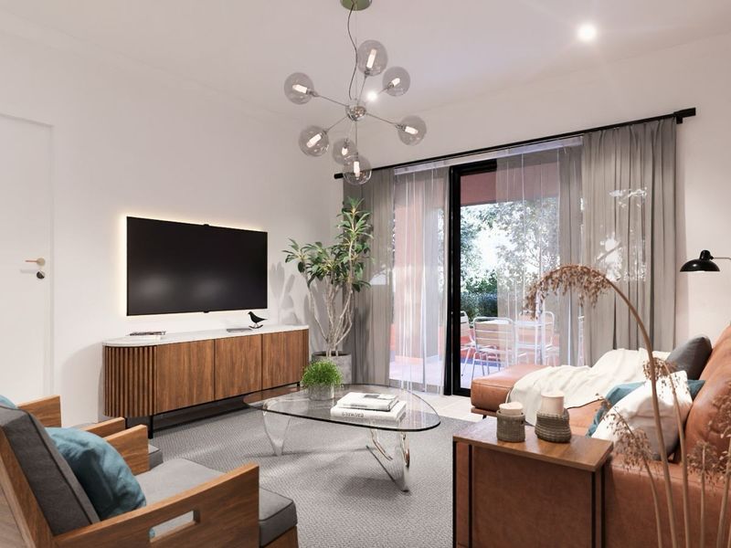A modern, well-lit living room featuring a sleek media wall, contemporary light fixture, and large sliding glass doors leading to an outdoor patio area.