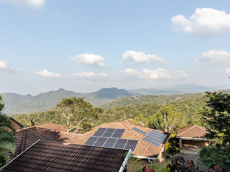 Elevated view overlooking the property roofline featuring installed solar panels with a scenic mountain landscape in the background.