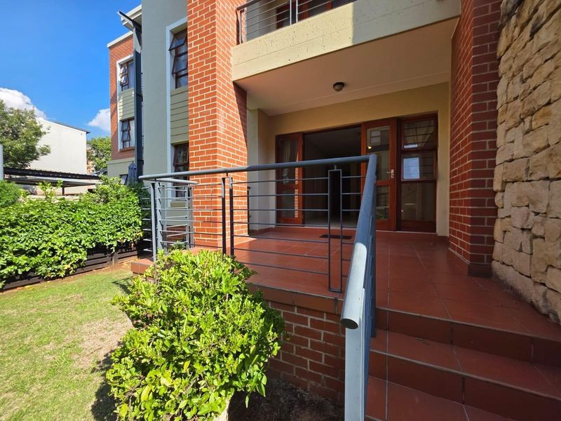A ground floor patio area featuring tiled flooring, a metal safety railing, and direct access to the apartment interior through glass doors.