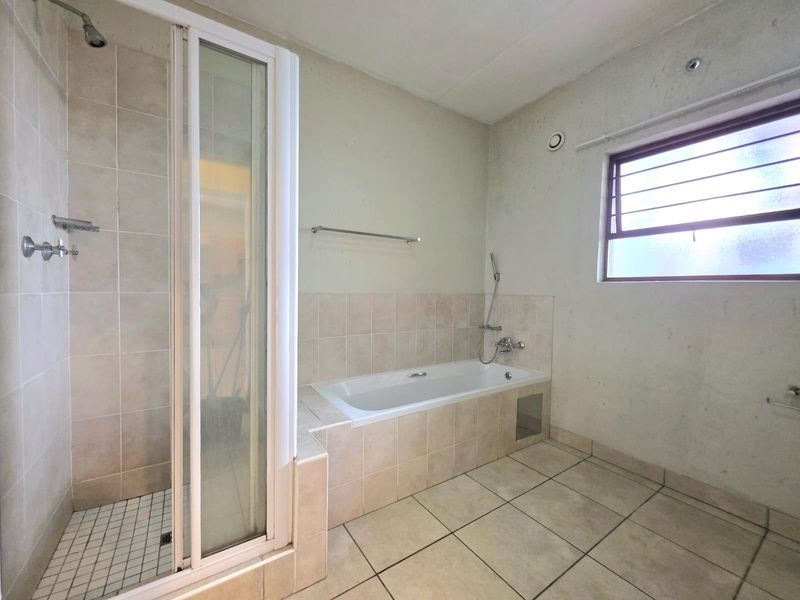 A functional bathroom featuring a separate shower enclosure, a built-in bathtub with tiled surround, and ceramic floor tiling.