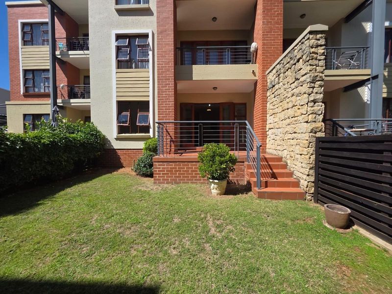 Ground floor apartment exterior featuring a private patio with brick steps, metal railings, and a small landscaped garden area.