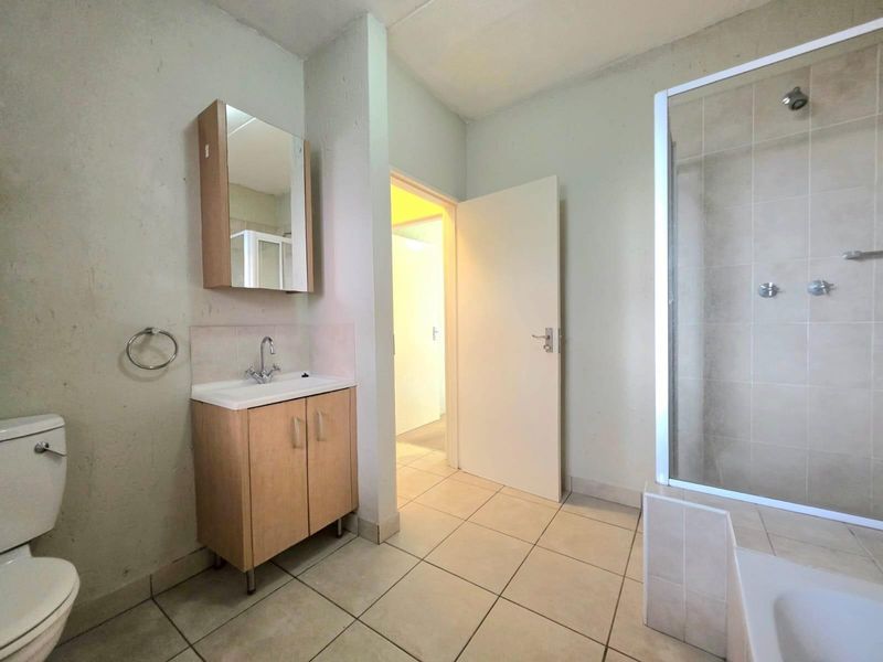 A functional bathroom featuring a vanity cabinet with mirror, a separate shower enclosure, and a standard toilet with tiled flooring.
