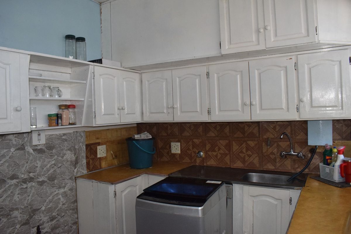 A functional kitchen area featuring white built-in cabinetry, tiled backsplash, and a stainless steel sink with laminate countertops.
