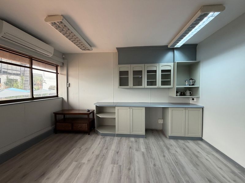 A clean, professional office space featuring built-in cabinetry, modern laminate flooring, and efficient overhead lighting, suitable for a productive work environment.