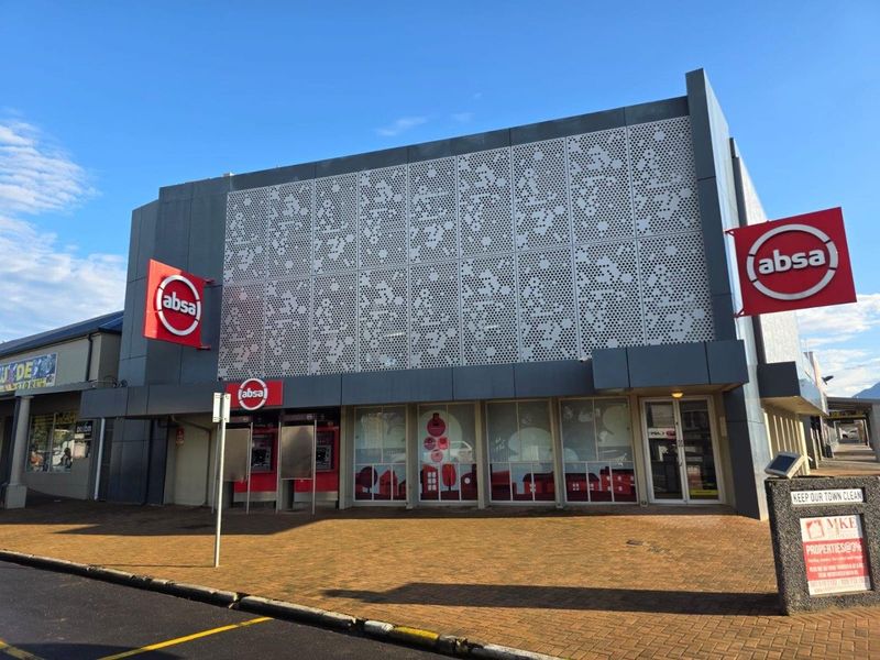 Commercial building facade featuring decorative perforated metal cladding, prominent corporate signage, and integrated street-level banking facilities with glass storefronts.