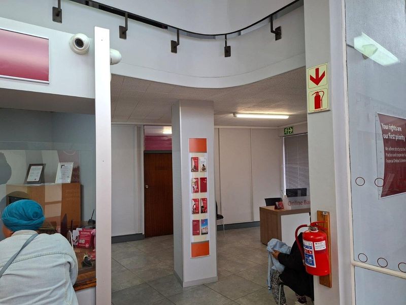 A commercial office interior featuring tiled flooring, a central structural column, integrated fire safety equipment, and a reception area.