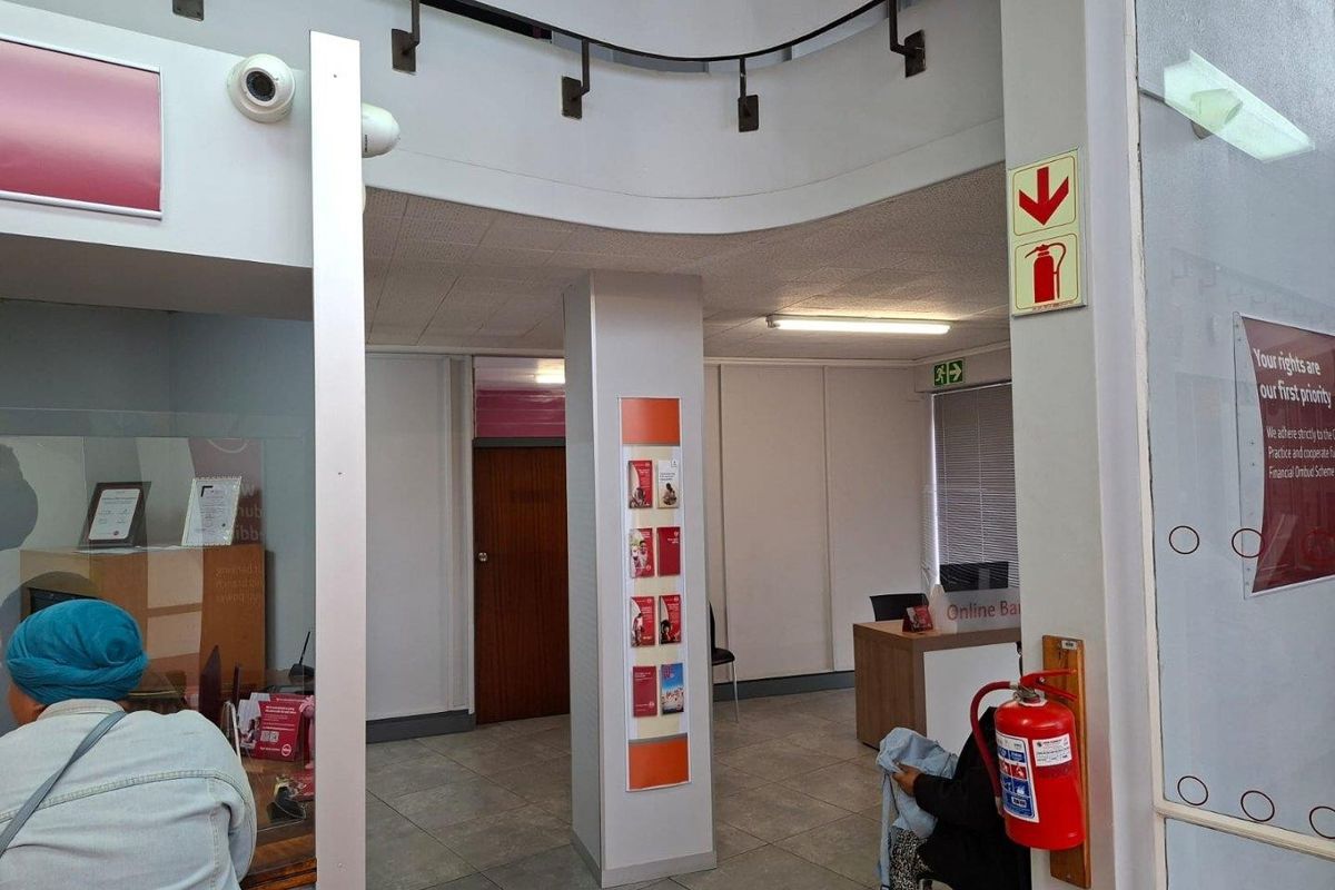 A commercial office interior featuring tiled flooring, a central structural column, integrated fire safety equipment, and a reception area.