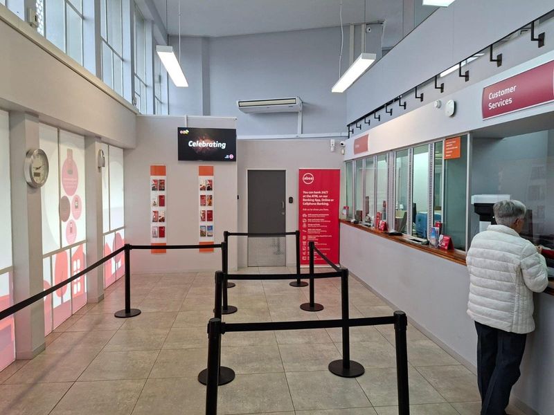 A clean and well-maintained commercial banking hall featuring a customer service counter, tiled flooring, and modern overhead lighting.