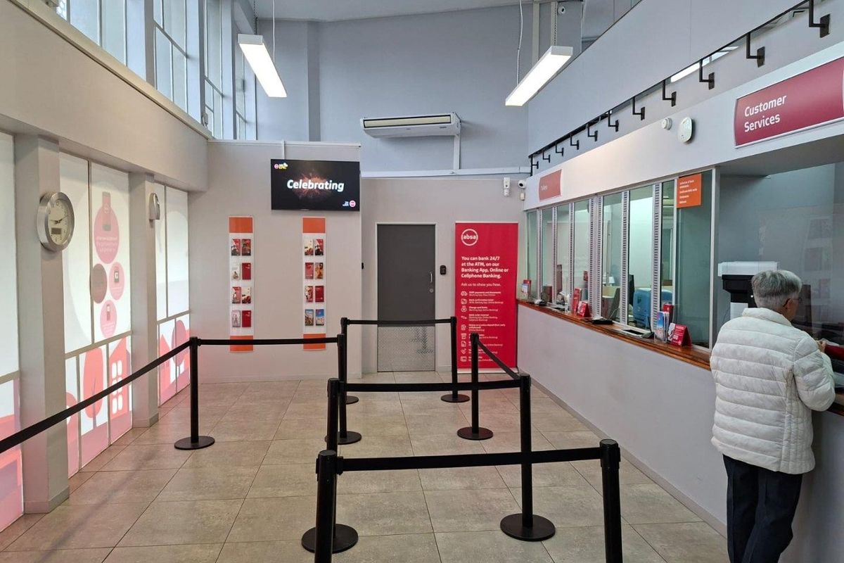 A clean and well-maintained commercial banking hall featuring a customer service counter, tiled flooring, and modern overhead lighting.