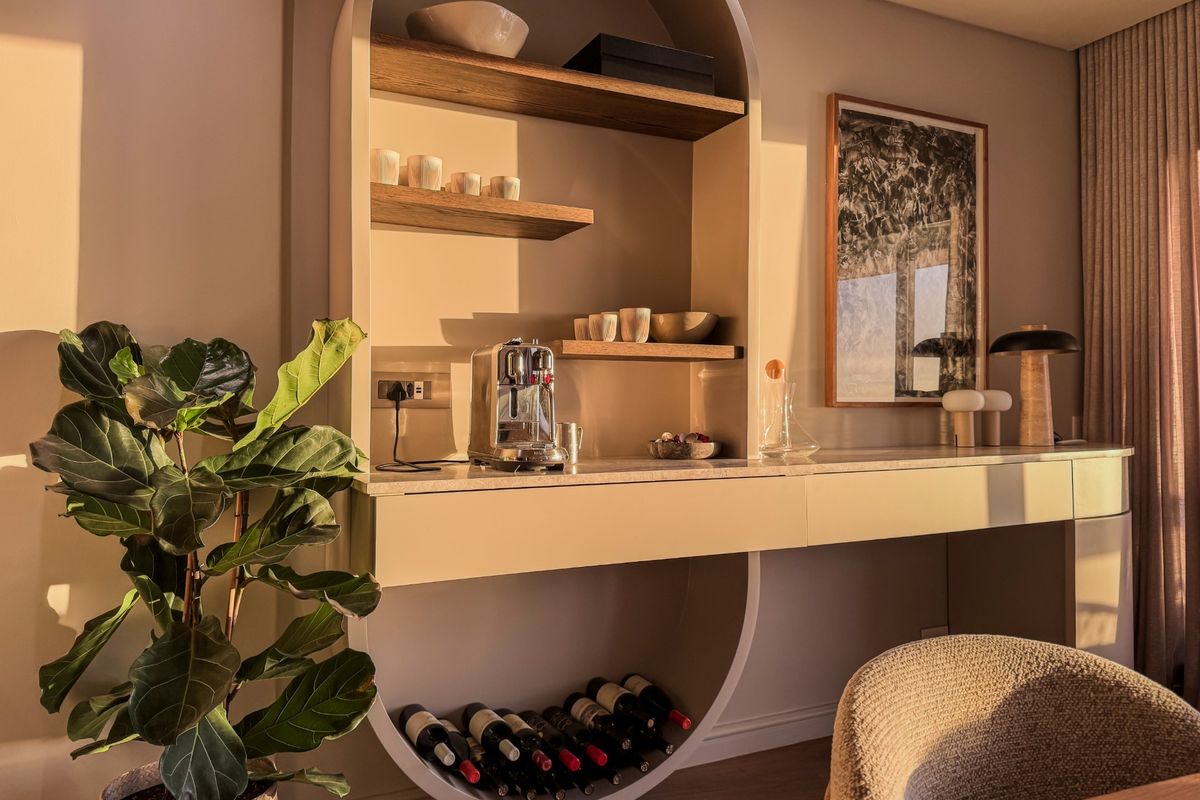 A modern, custom-built integrated shelving unit featuring sleek cabinetry, stone countertop, and a dedicated circular wine storage section.
