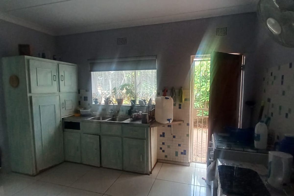 A functional kitchen featuring built-in cabinetry, a double-basin sink, and direct access to an outdoor area through a security door.