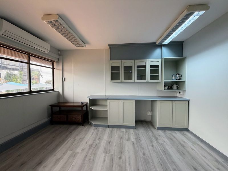 A clean, professional office space featuring built-in cabinetry, laminate flooring, and efficient split-system air conditioning, providing a functional work environment.