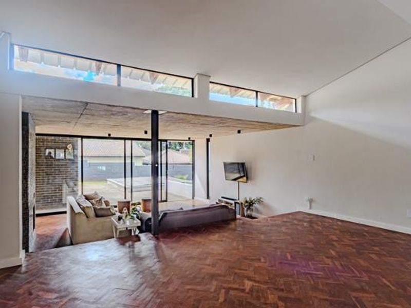 Spacious living area featuring beautiful herringbone parquet flooring, exposed concrete ceilings, and large sliding glass doors that open to the outdoor patio.