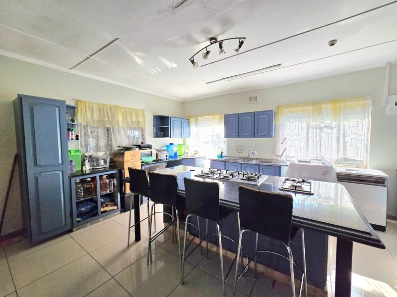 Spacious kitchen featuring a central island with a built-in gas hob, blue cabinetry, and tiled flooring throughout.