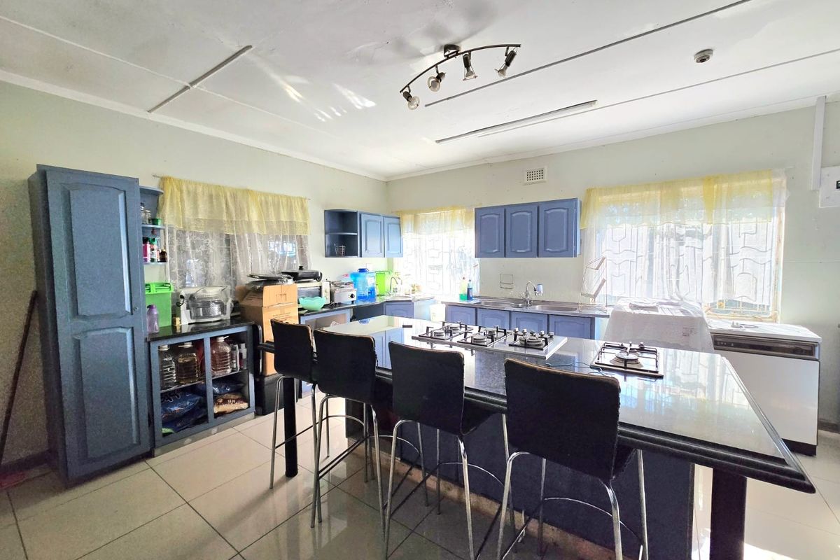 Spacious kitchen featuring a central island with a built-in gas hob, blue cabinetry, and tiled flooring throughout.