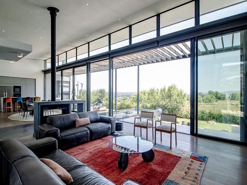 Spacious open-plan living area featuring floor-to-ceiling sliding glass doors, a modern freestanding fireplace, and seamless flow to the outdoor patio and garden.