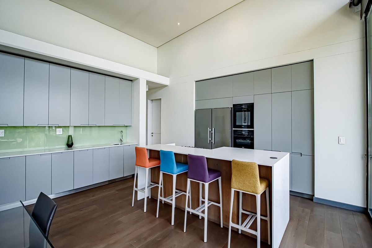 Modern kitchen featuring sleek grey cabinetry, a central island with breakfast bar, integrated appliances, and high-quality finishes throughout.