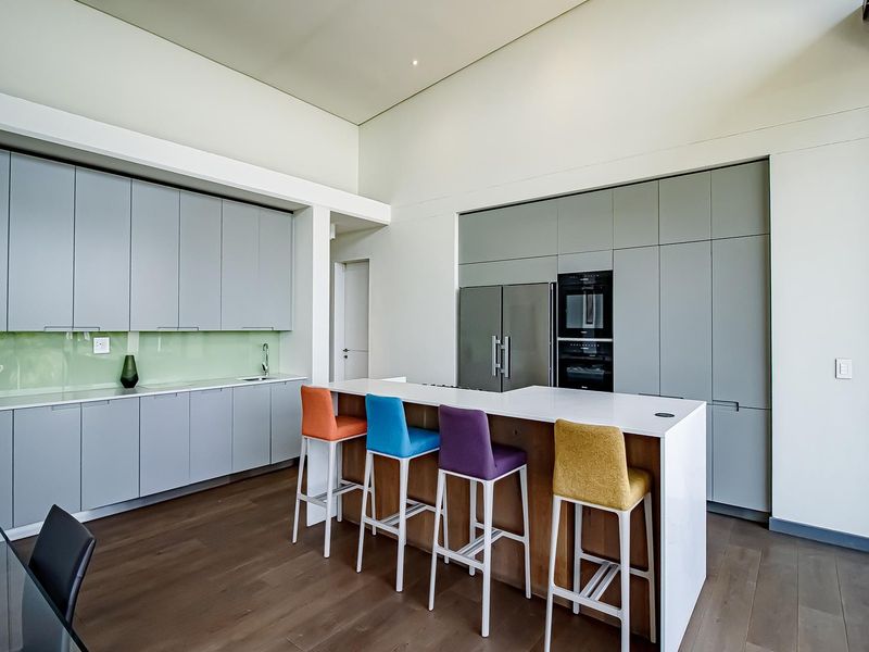 Modern kitchen featuring sleek grey cabinetry, a central island with breakfast bar, integrated appliances, and high-quality finishes throughout.