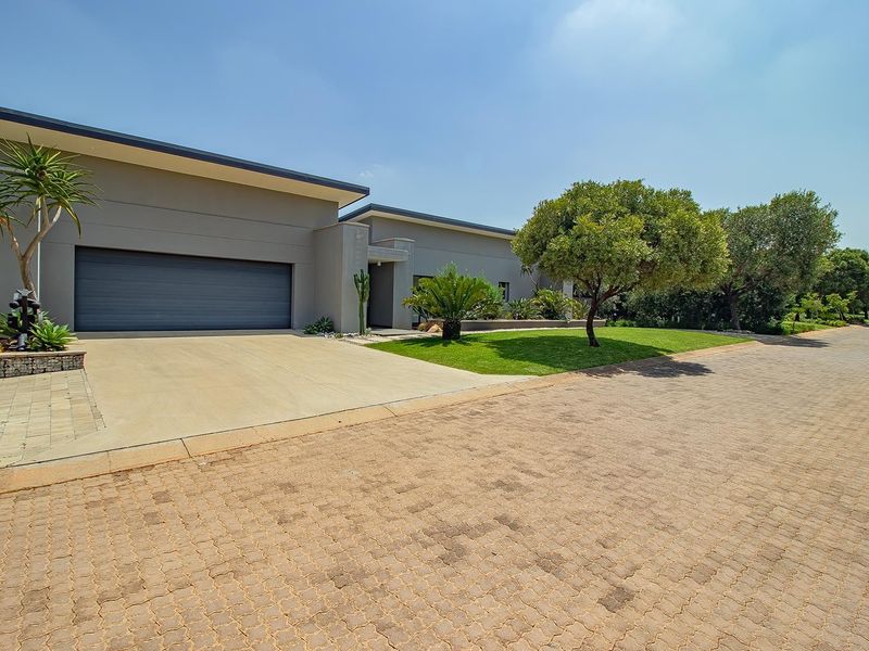 Modern single-story residence featuring a double garage, concrete driveway, and well-maintained landscaped front garden.