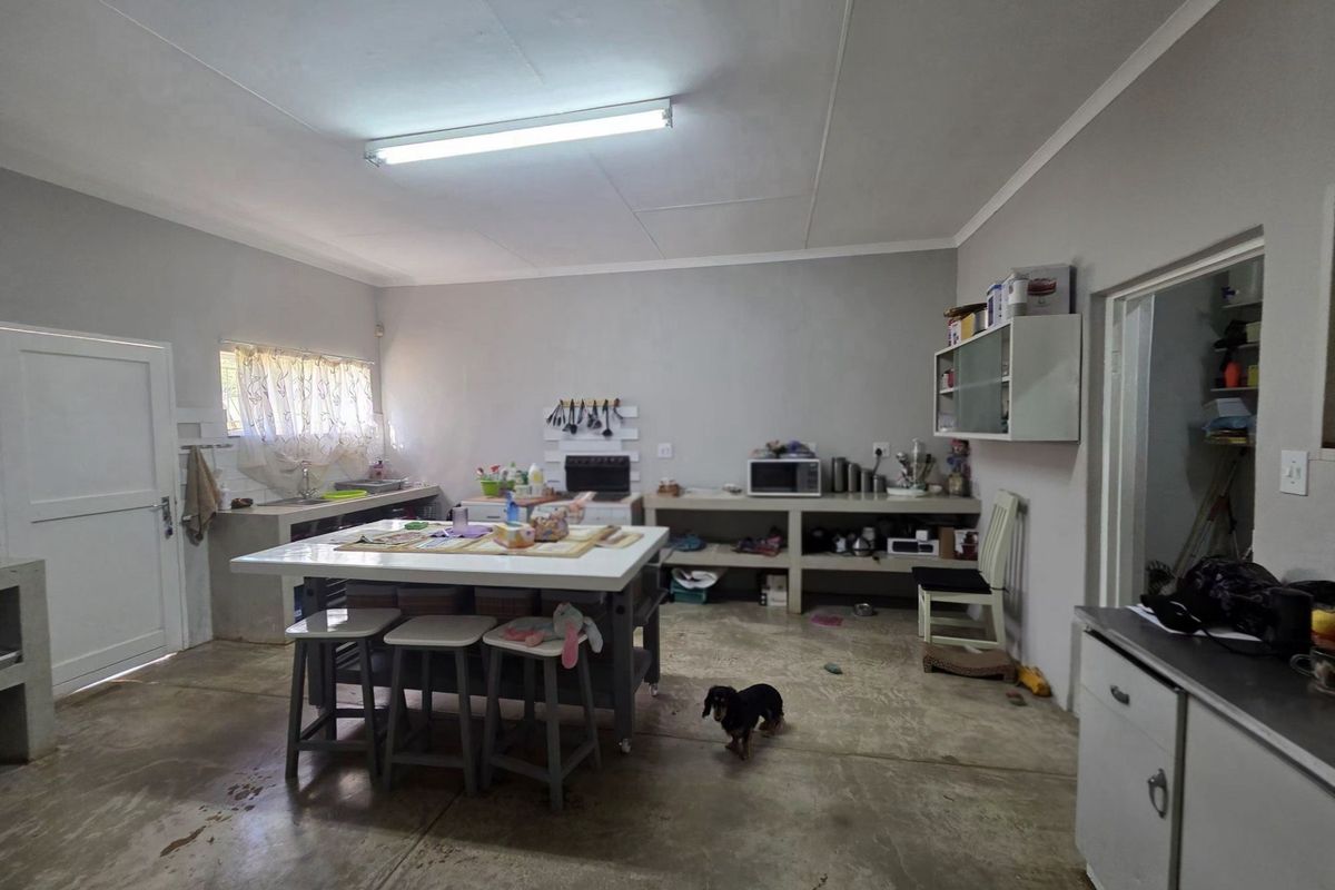 A rustic kitchen area featuring concrete countertops, built-in shelving, and concrete flooring, offering a functional space with potential for modern updates.