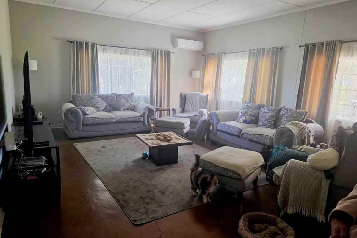 Spacious living room featuring tiled flooring, split-system air conditioning, and large windows with curtain rails, offering a comfortable and functional family space.
