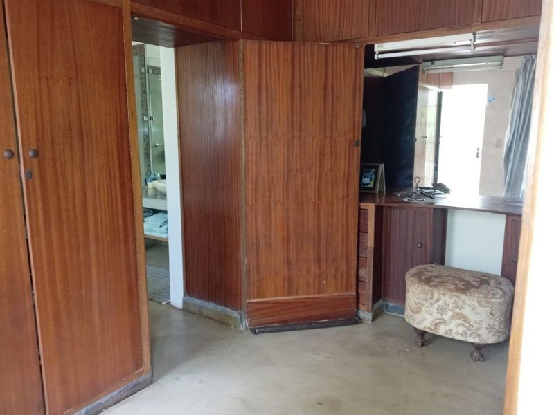 A bedroom featuring extensive built-in wooden cabinetry and a vanity area, with direct access to an en-suite bathroom.