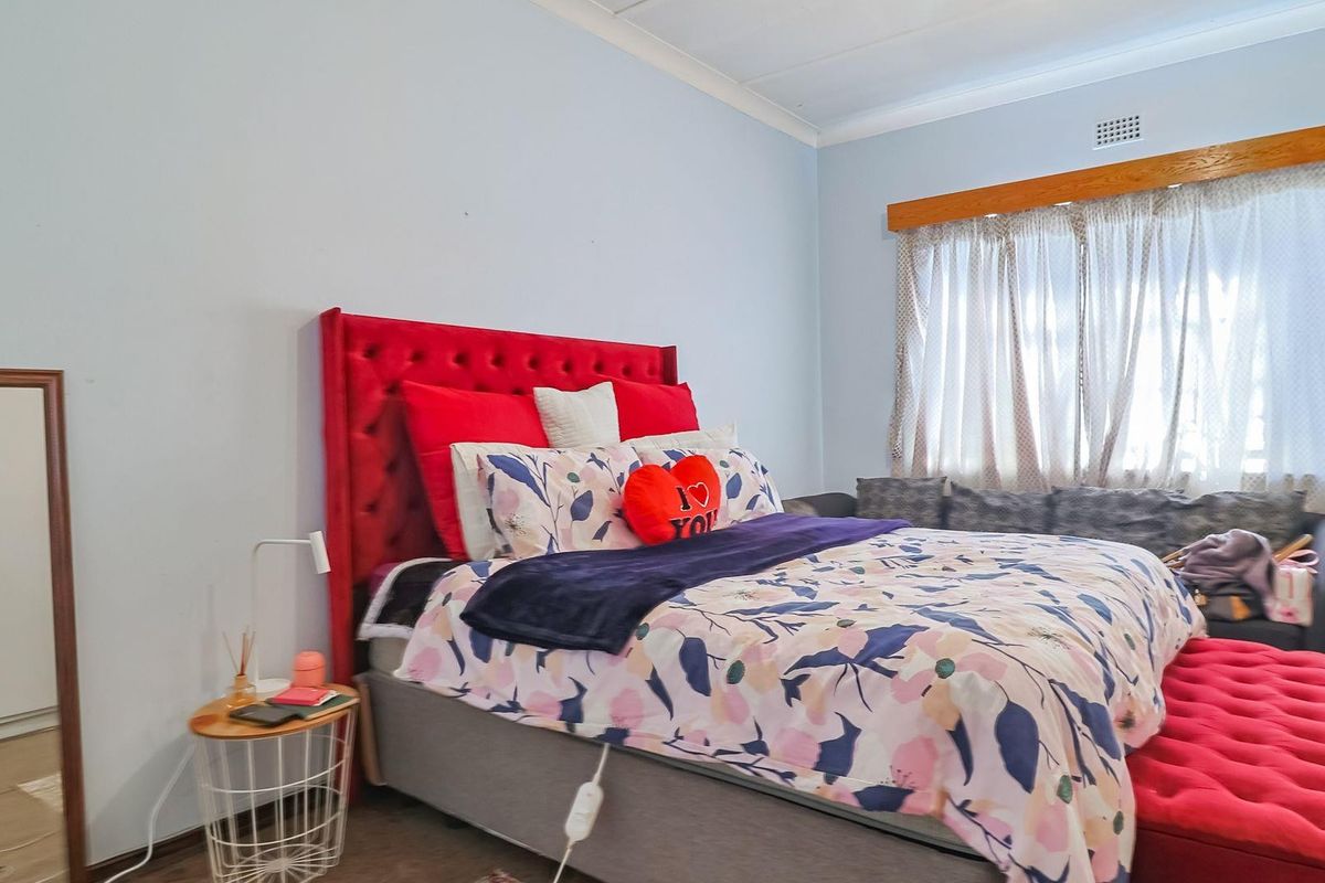 A bedroom featuring a window with a wooden pelmet and a ceiling vent.