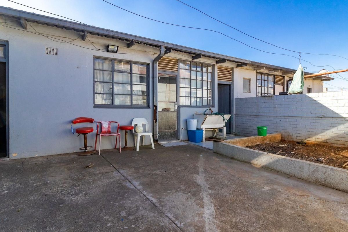Rear exterior view of the property featuring a concrete patio area, a raised garden bed, and access to the rear building facade.