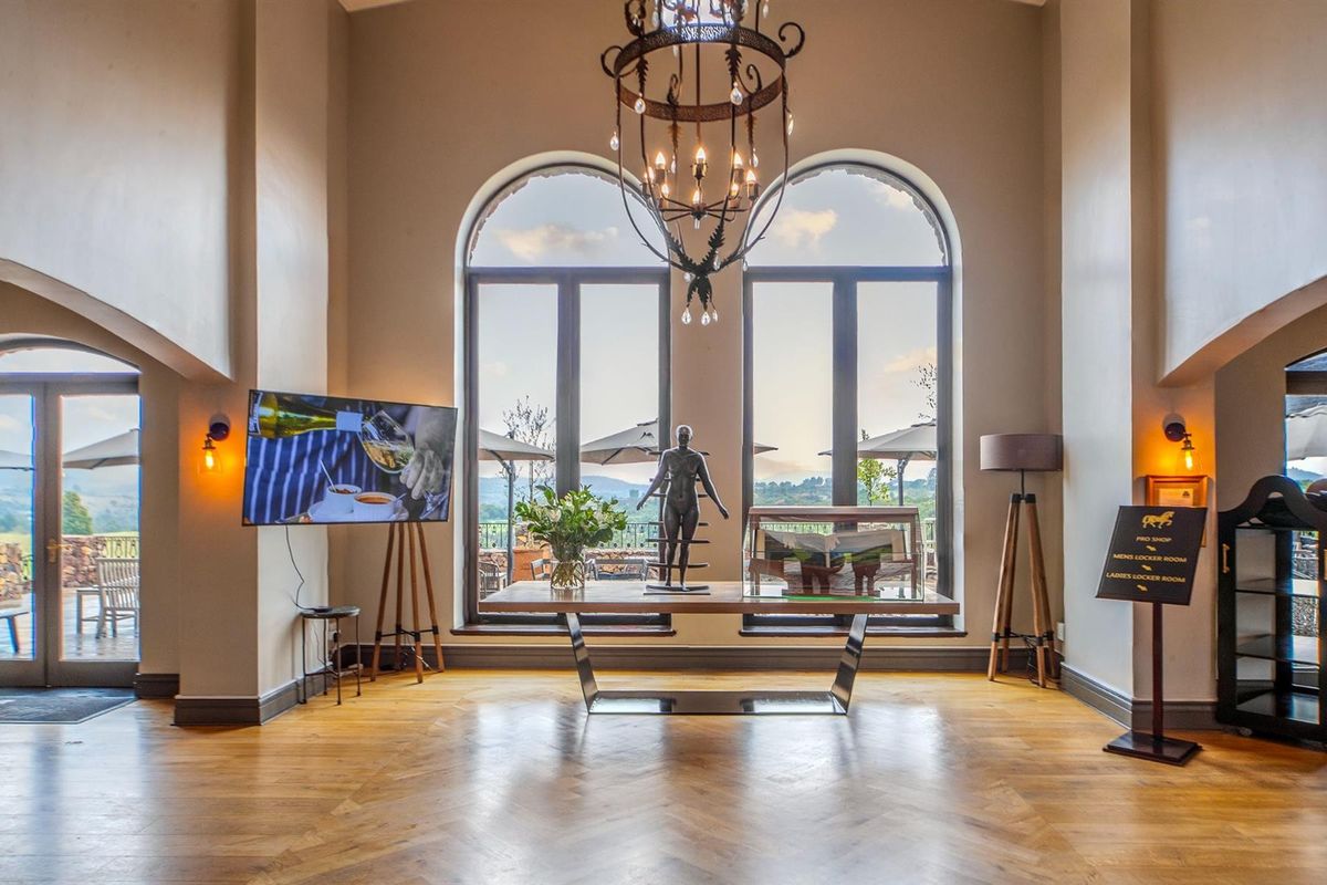 Elegant living area featuring high ceilings, arched windows with scenic views, hardwood flooring, and a decorative wrought iron chandelier.