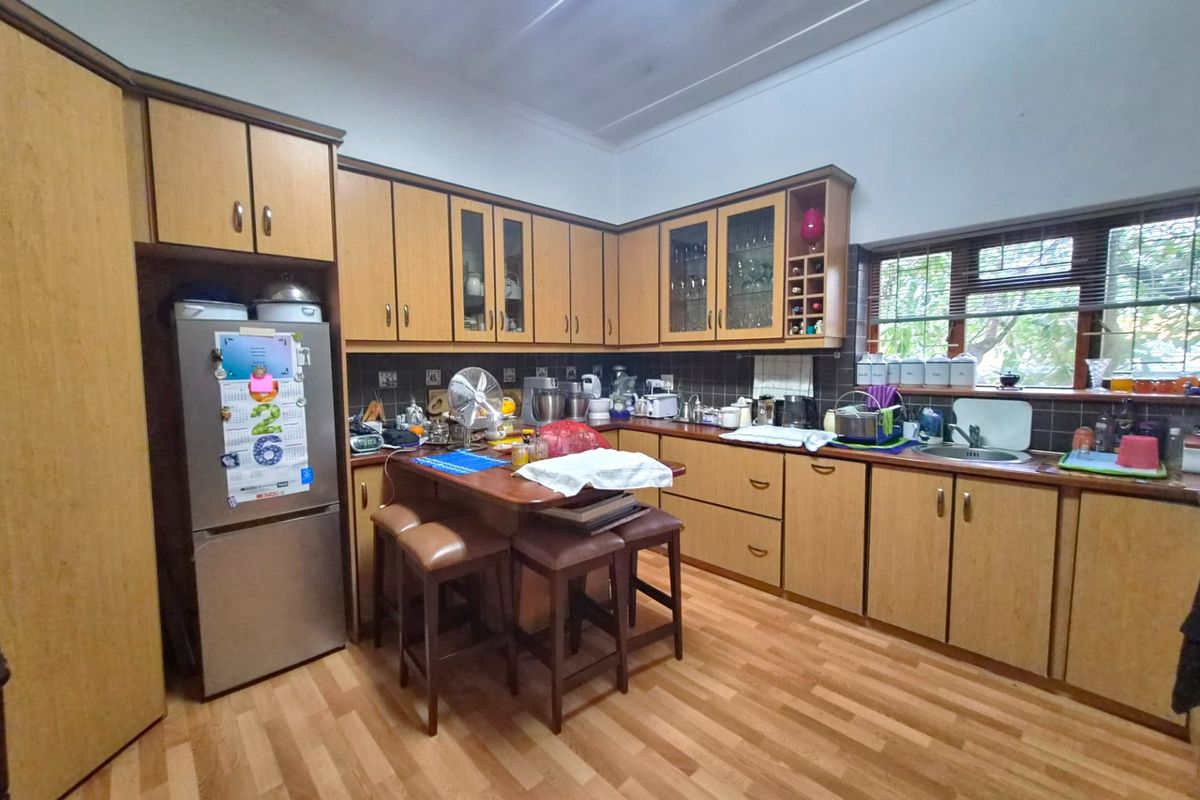 A functional kitchen featuring wood-toned cabinetry, laminate countertops, a built-in breakfast nook, and a tiled backsplash with a view of the garden.