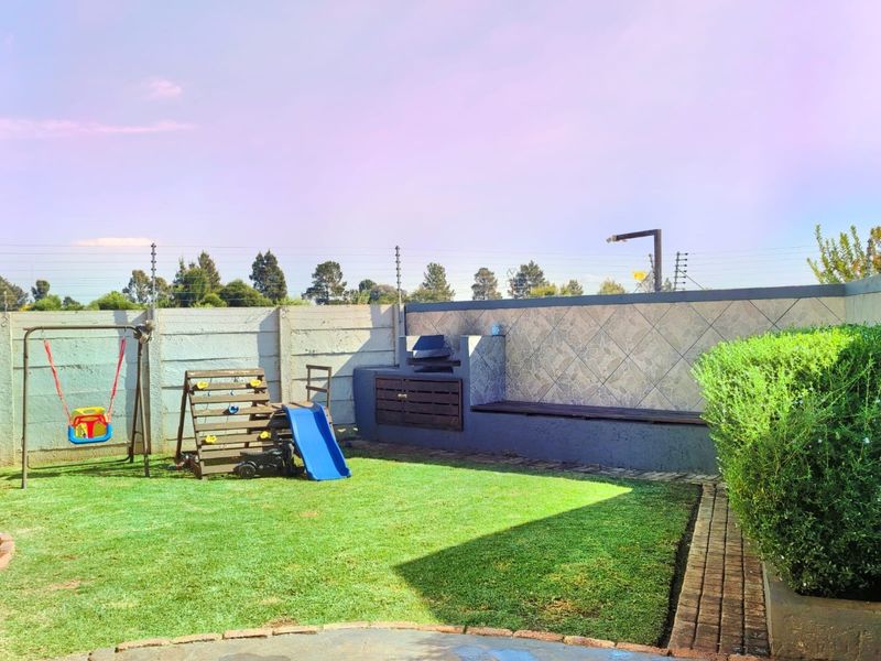 Private rear garden featuring a built-in braai area, paved patio space, and established lawn, enclosed by perimeter walling.