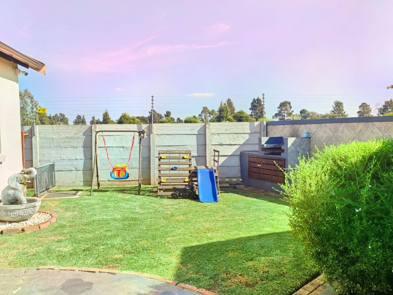 Private rear garden featuring a built-in brick braai area, lawn space, and perimeter concrete walling.