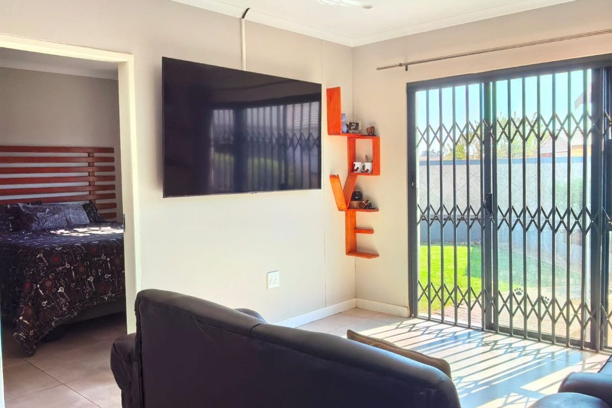 Living room featuring tiled flooring, recessed ceiling lighting, and sliding glass doors with security gates leading to the rear garden.