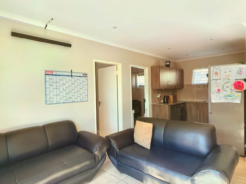 Open plan living area featuring tiled flooring and a compact kitchen with built-in cabinetry.